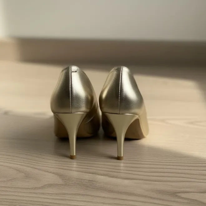 Pair of gold high-heeled shoes on a wooden floor