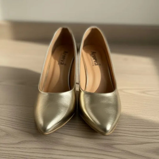 Pair of gold pointed-toe shoes on a wooden surface