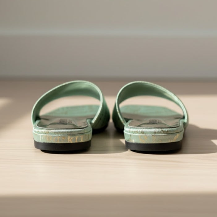 Pair of green sandals on a wooden surface with a neutral background