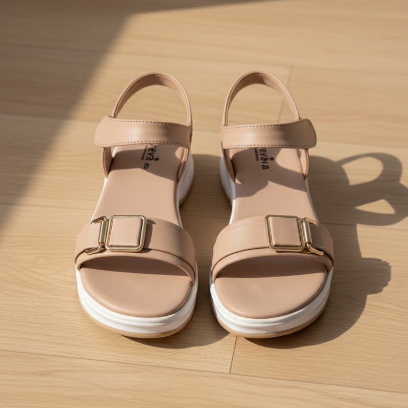 Pair of beige sandals with buckles on a wooden surface