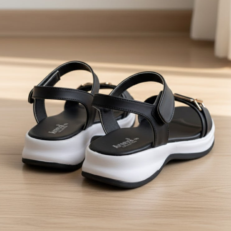Black sandals with white soles on a wooden floor
