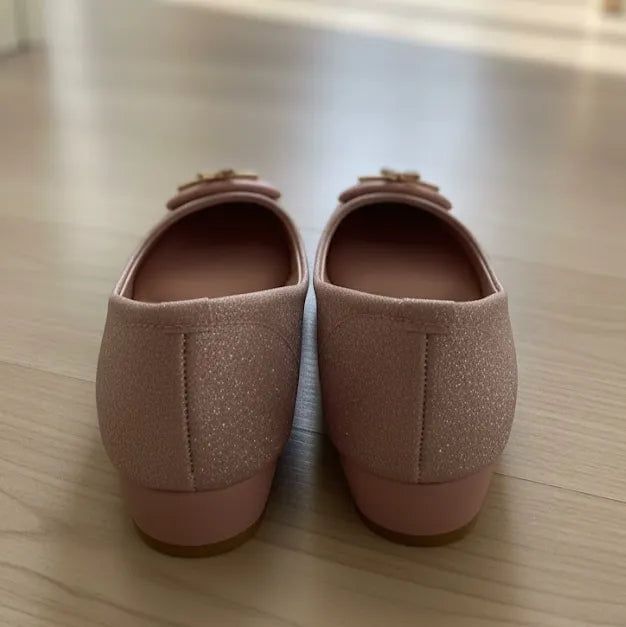 Pair of pink glittery shoes on a wooden floor
