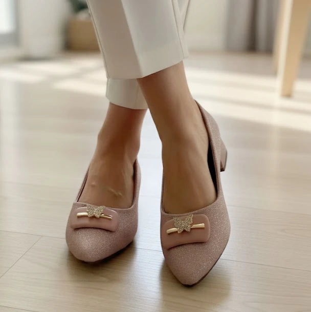 Pink shoes with decorative bows worn indoors on a light wooden floor.
