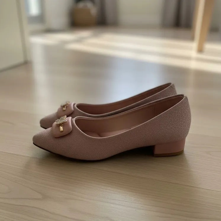 Pair of pink shoes with decorative bow on a wooden floor