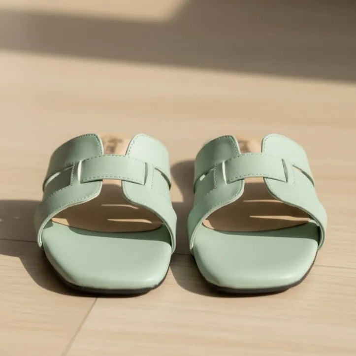 Pair of light green slipper on a beige surface