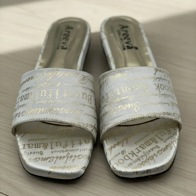 Pair of white chappal with text on a wooden surface